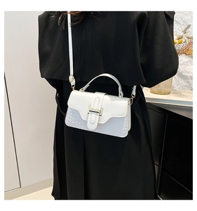 Chic white leather handbag with gold buckle shown on a black coat outfit for styling