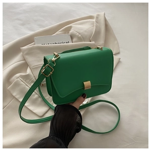 Detailed view of green leather baguette bag with golden buckle and adjustable strap