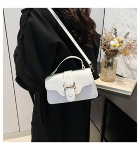 Detail of white PU leather crossbody bag featuring crocodile pattern and gold metal buckle