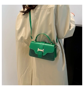 Detail of green crossbody bag with textured leather and gold H buckle on model