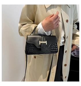 Close-up of black crossbody bag with crocodile texture and gold H-clasp closure