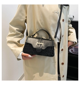 Close-up of black crossbody bag featuring elegant crocodile texture and silver buckle
