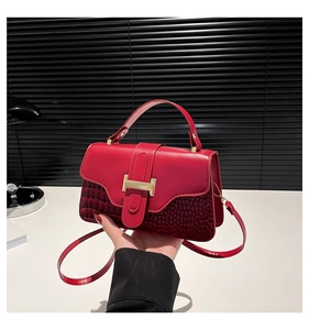Detail of red leather crossbody bag featuring gold H-shaped buckle and crocodile texture