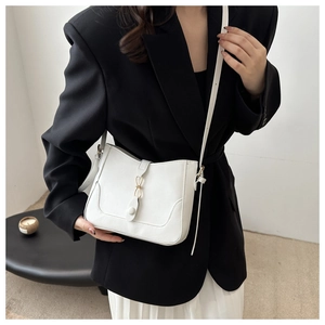 Chic white leather shoulder bag with gold metal buckle on female model in black blazer