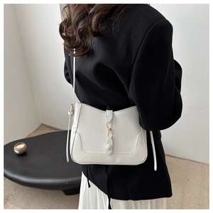 Detail of white leather shoulder bag with gold metal ring and adjustable strap on model