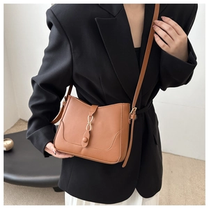 Chic brown leather bucket bag shown on a model, featuring a gold ring buckle detail