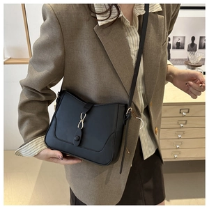 Detail of a black leather shoulder bag featuring a decorative golden knot buckle closure