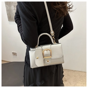 Silver metallic crossbody bag featuring square buckle detail and small accessory pouch