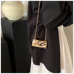 Detailed close-up of a gold mini chain bag with liquid metal texture and wrinkled design