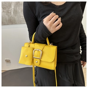 Detail of yellow crossbody bag with oversized gold buckle and detachable mini coin purse