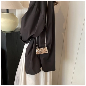 Detail of liquid gold metallic crossbody bag showing pleated texture and chain strap