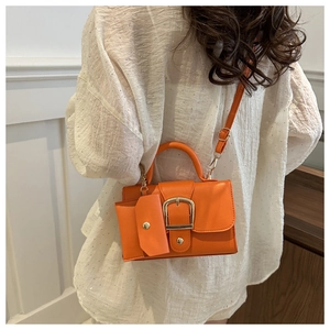 Bright orange crossbody bag with metal buckle and matching small pouch on a model