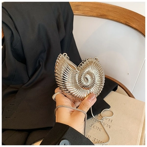 Detail view of a silver nautilus-shaped clutch bag with spiral metallic ridges and chain