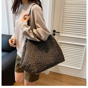 Detailed view of leopard print canvas tote bag on shoulder with wide strap design