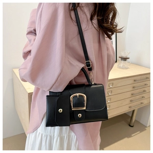 Detail of a vintage black crossbody bag with gold buckle and a mini hanging pouch