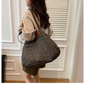 Close-up of leopard print canvas tote bag with brown leather patches and dual handles