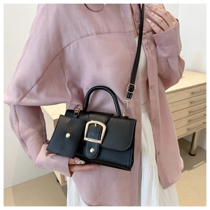 Detail of black square tote with gold metal buckle and detachable mini pouch accessory