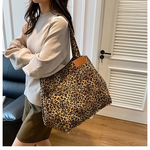 Close-up of a leopard print canvas tote bag with a brown leather patch on a lifestyle model