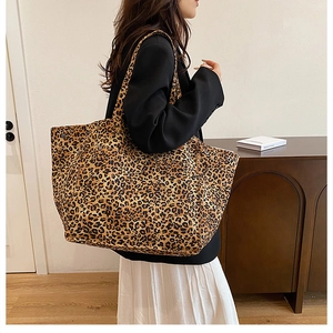 Detailed side view of a large leopard print canvas tote bag styled on a female model