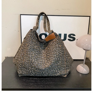 Detail of leopard print canvas tote bag with brown leather tag on a black desk