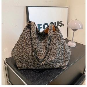 Detailed view of leopard print canvas tote bag with front pocket on a stylish office desk