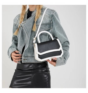 Close-up of contrast black and white leather handbag worn with a denim jacket