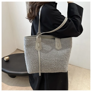 Detail of grey fuzzy faux shearling tote bag with smooth leather straps for winter style