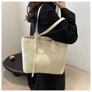 Dettaglio della borsa tote in peluche crema con manici in pelle indossata dalla modella
