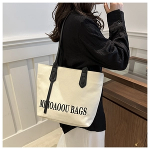 Detailansicht der weißen Segeltuch-Tasche mit schwarzen Lederriemen und Aufdruck