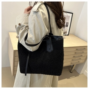 Détail d'un grand sac cabas noir en polaire avec anses en cuir sur un mannequin femme