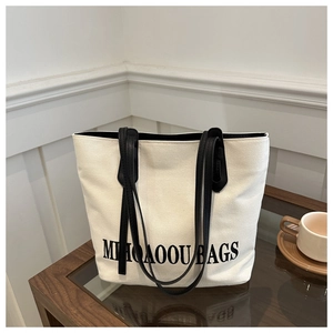Nahaufnahme der cremefarbenen Canvas-Tasche mit schwarzem Aufdruck auf einem Holztisch