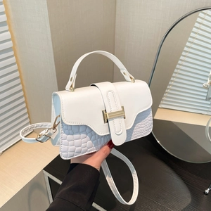 Chic white crossbody bag with crocodile texture and gold H-lock in a home setting