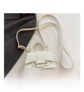 Close-up of geometric woven texture and gold buckle on white faux leather mini bag