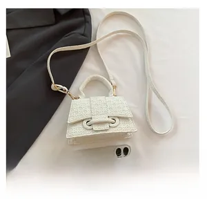Detailed view of white embossed mini bag with shoulder strap next to phone for scale