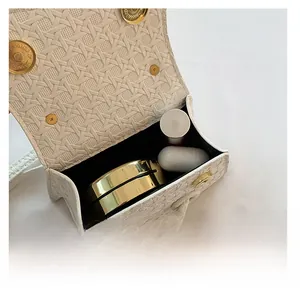 Interior view of small woven crossbody bag with makeup items and golden magnetic closure