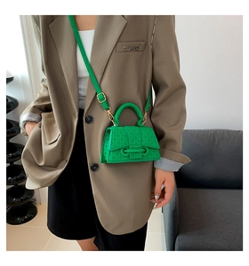 Close-up of bright green hourglass handbag with geometric texture and gold hardware