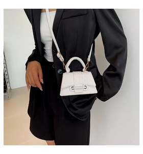 White mini crossbody bag with embossed texture and gold hardware on model in black suit