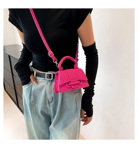 Detail view of hot pink mini crossbody bag with textured geometric pattern and strap
