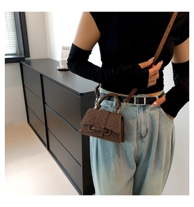 Detail of dark brown mini crossbody bag with embossed interlocking weave texture on a model