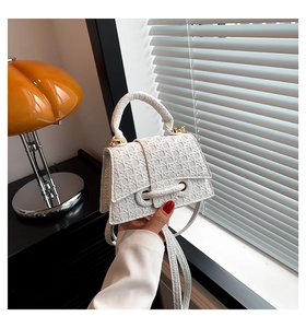 Detail of white mini handbag with geometric weave texture and stylish B-shaped buckle