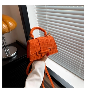 Detail of orange woven texture handbag with golden hardware and adjustable strap