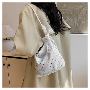 Detail of white polka dot shoulder bag featuring delicate lace trim and large bow detail