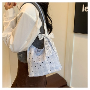 Close-up of light blue bucket bag with black polka dots and a large white lace bow detail
