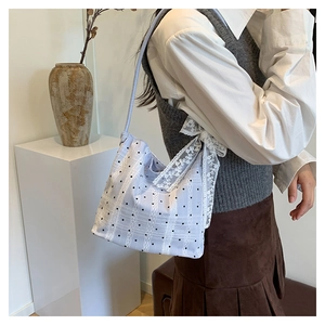 Close-up of pastel plaid shoulder bag with delicate white lace trim and bow detail