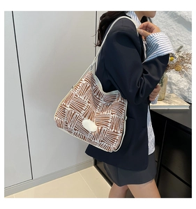 Détail d'un sac seau tissé avec motif jacquard marron et bandoulière en cuir blanc