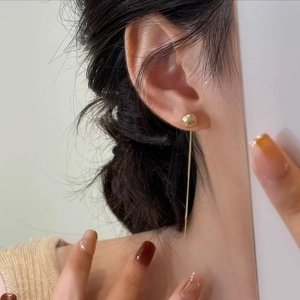 Minimalist gold long tassel chain earrings with spherical studs on female model