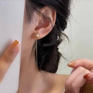 Elegant gold pearl drop earrings with long tassel chains shown on model for a sleek look