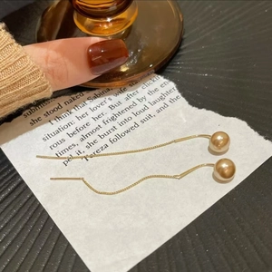 Elegant gold long tassel earrings with champagne beads on vintage book background