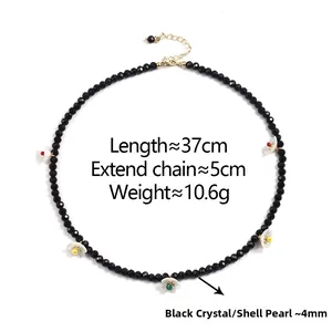 Detailed view of beaded necklace with black crystals, white flower motifs and gold extender