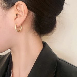 Boucles d'oreilles créoles dorées géométriques avec pavé de diamants sur un mannequin